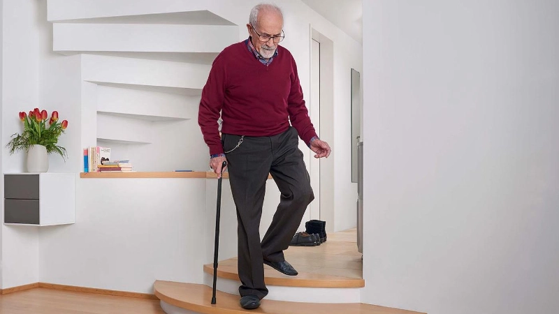 Mann mit Gehstock geht Treppe runter