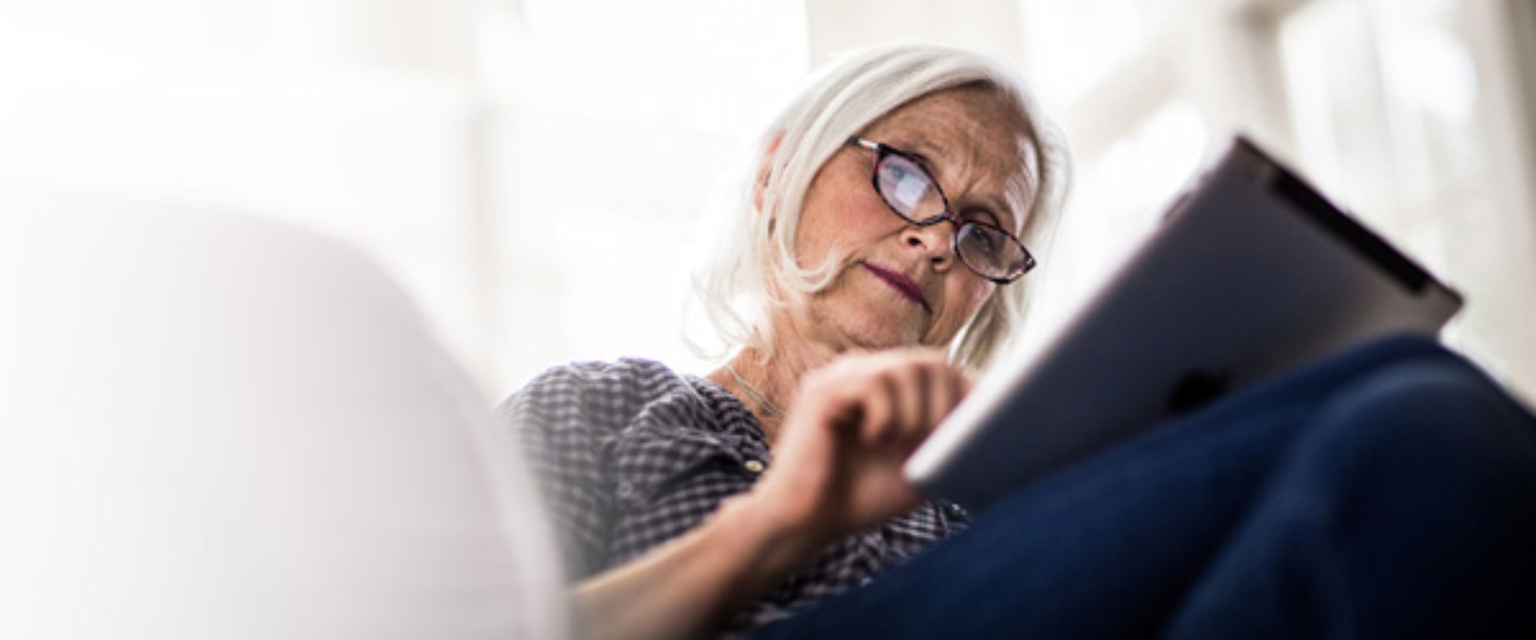 Eine Seniorin, die etwas am Laptop macht.