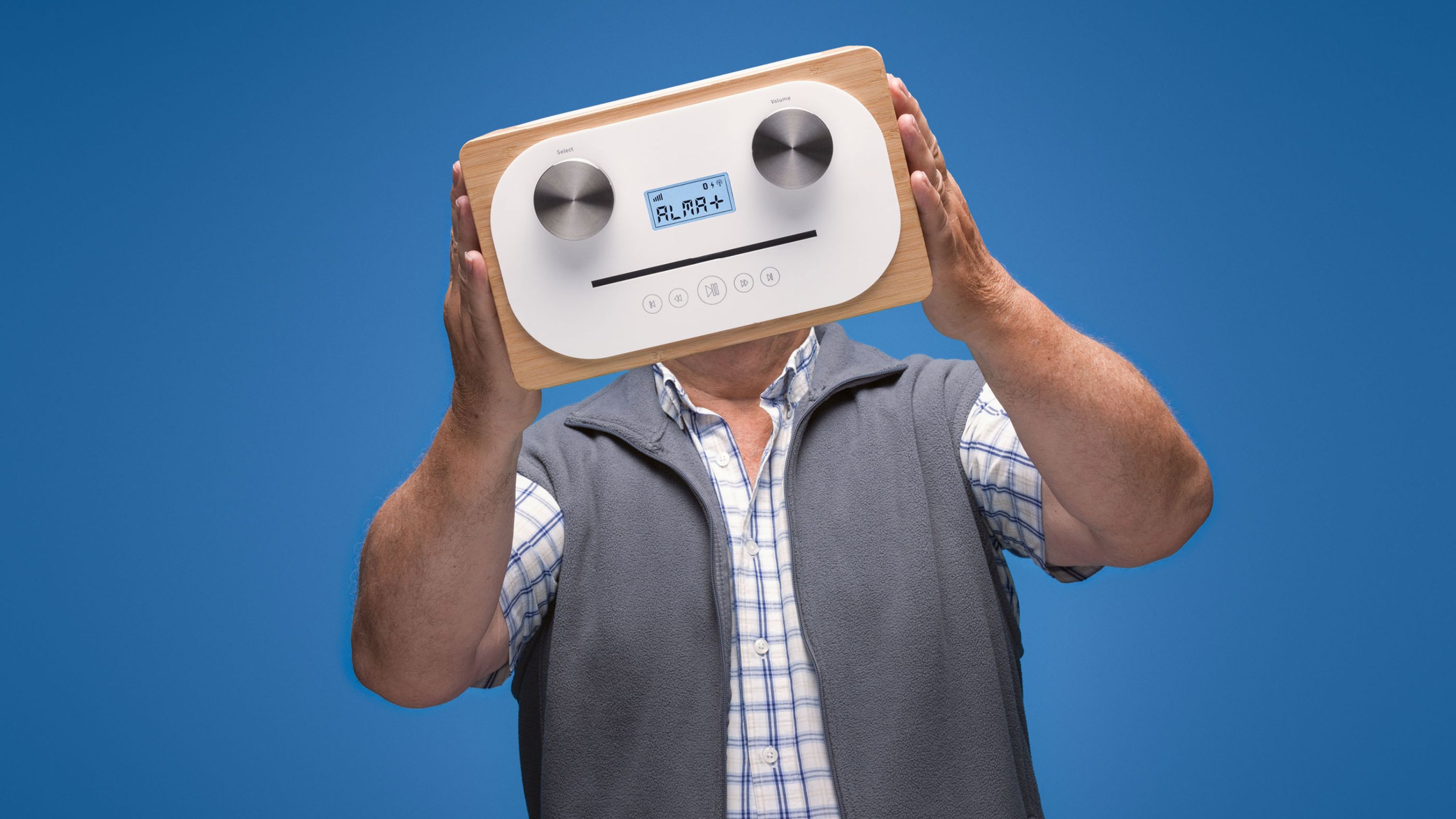 Un homme âgé tient sa radio DAB dans ses mains devant son visage.